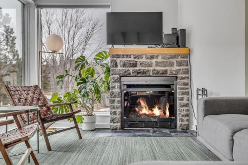 Una sala de estar con chimenea y un televisor encima. en Initial - Hygge - MSA, en Beaupré