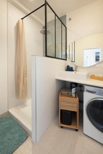 une salle de bain avec un lavabo et une machine à laver dans l'établissement Vue sur la place Wilson - Appt spacieux et lumineux, à Brest