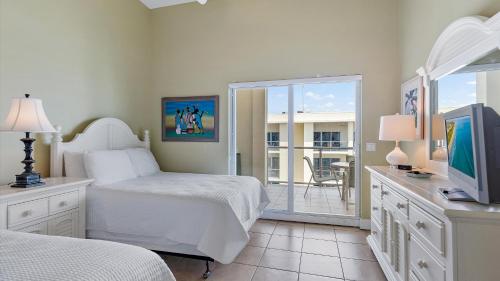 a bedroom with a bed and a television and a balcony at Crescent Siesta Key Charmer in Siesta Key