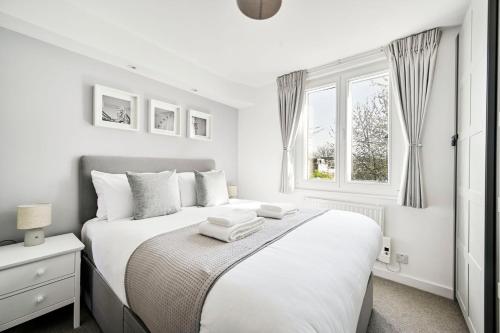 a white bedroom with a bed and a window at GuestReady - Central London stay near King's Cross in London
