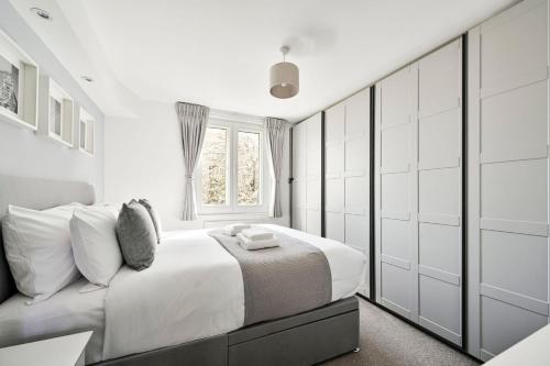 a white bedroom with a large bed and a window at GuestReady - Central London stay near King's Cross in London