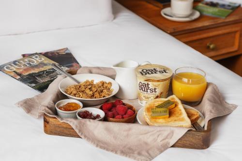a tray of breakfast food on a bed with orange juice at The County Hotel in Carlisle