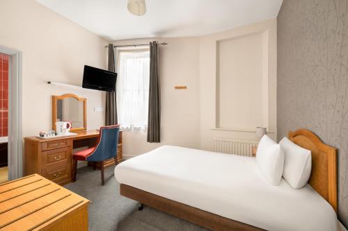 a hotel room with a bed and a desk and a chair at The County Hotel in Carlisle