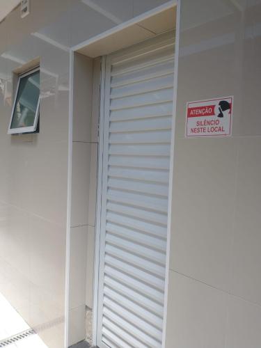 a white garage door with a sign on the side of a building at Suíte aconchegante a 10 min do aeroporto in Guarulhos