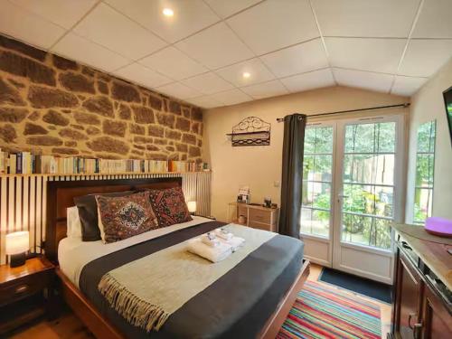 une chambre avec un grand lit et un mur en pierre dans l'établissement Capelle House, à La Capelle-Bonance