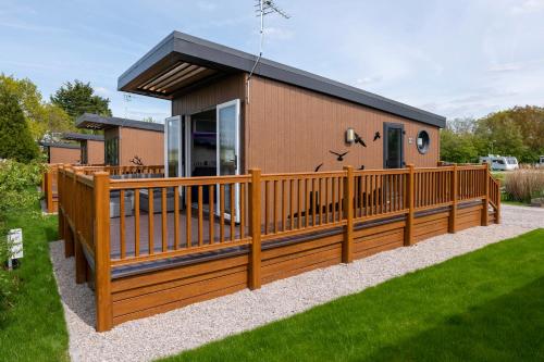 a house with a wooden fence and a yard at Royal Umpire Caravan Park in Croston