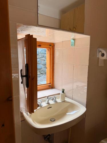 a bathroom sink with a mirror and a window at CASA VACANZE NORA in Chamois