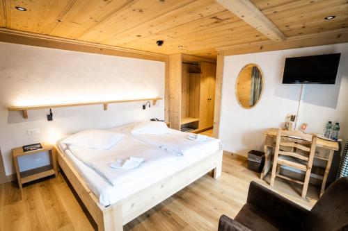 a bedroom with a bed and a desk with a television at Posthotel Rössli in Gstaad
