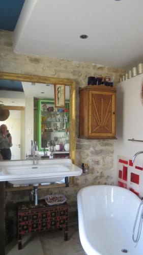 une salle de bain avec une baignoire, un lavabo et un miroir dans l'établissement Maison colorée, jardin et studio, à Avignon