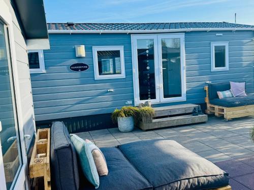 a blue house with a couch on a patio at Zeeuws Ibiza huisje in Kamperland