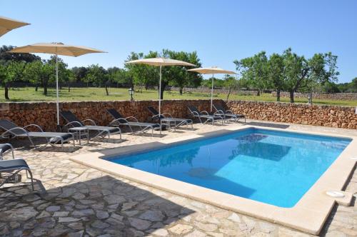 a swimming pool with chairs and umbrellas at Can Porretí Agroturisme in Lloret de Vistalegre