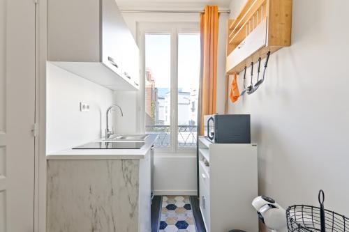 une petite cuisine avec un évier et une fenêtre dans l'établissement Studio calme en plein Paris, à Paris