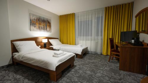 a hotel room with two beds and a desk and a television at Forrest in Głogów Małopolski