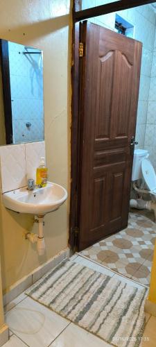 a bathroom with a sink and a wooden door at Mwango Deluxe Apartments in Voi