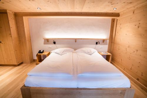 a bedroom with a white bed in a wooden room at Posthotel Rössli in Gstaad