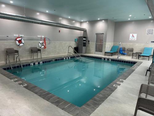 a large swimming pool with chairs and chairs around it at avid hotel Harrisburg NE - Hershey Area by IHG in Harrisburg