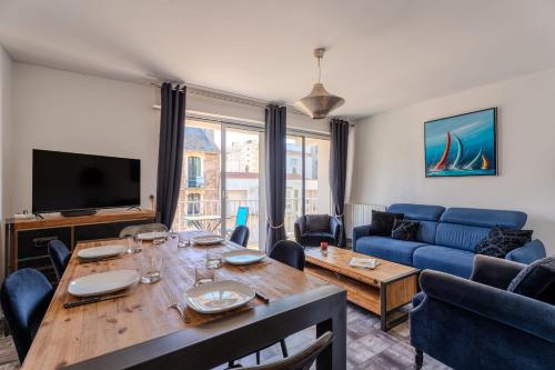 un salon avec une table et un canapé bleu dans l'établissement Appartement Moderne & Confort Accès Plage et Commerces, à Les Sables-dʼOlonne