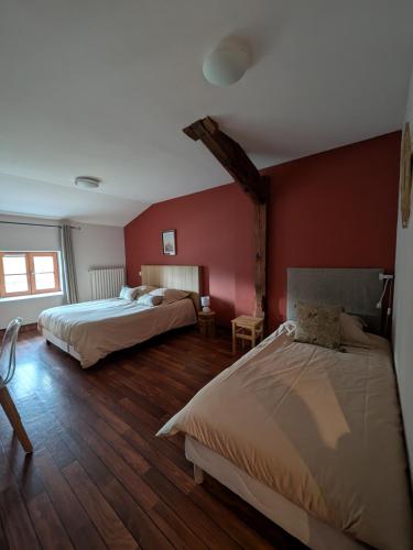 two beds in a room with red walls and wooden floors at L'Estampille in Saint-Vidal