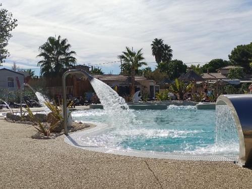 une fontaine dans une piscine du complexe dans l'établissement MOBIL HOME le MARTINET, à Sérignan