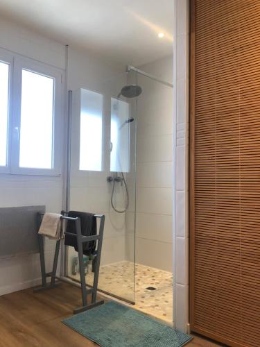 un bagno con doccia con sedia e porta in vetro di Maison au coeur de Capbreton a Capbreton