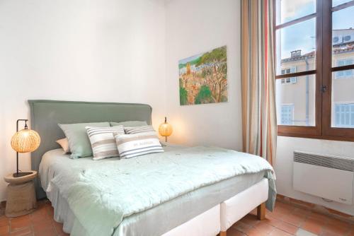 Un dormitorio con una cama con dos lámparas y una ventana. en Saint Esprit, en Saint-Tropez