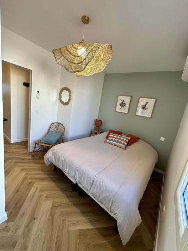 une chambre avec un grand lit et un lustre dans l'établissement LeBellevue, à Sanary-sur-Mer