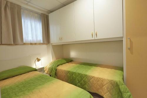 two beds in a small room with white cabinets at Village Camping Joker in Cavallino-Treporti