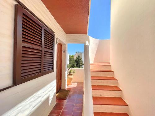 a hallway of a house with stairs and a window at Edificio Rex I ES.01 2ª PT.04 in Es Pujols