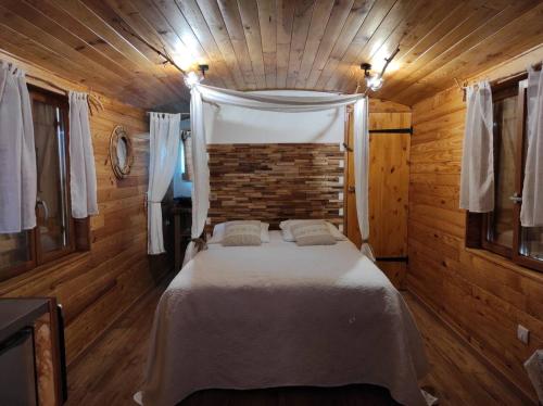 une chambre avec un lit dans une cabane en bois dans l'établissement Roulotte à la campagne avec son spa à Cabariot, à Cabariot