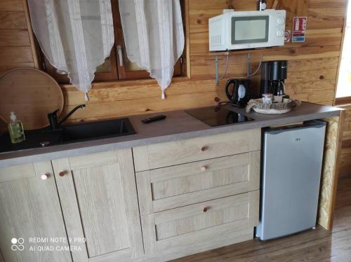 a kitchen with a white refrigerator and a microwave at Roulotte à la campagne avec son spa à Cabariot in Cabariot