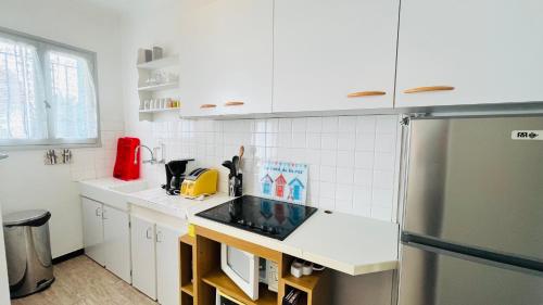 La cuisine blanche est équipée d'un évier et d'un réfrigérateur. dans l'établissement Appart des Tamaris, 200m de la plage, à Saint-Jean-de-Monts
