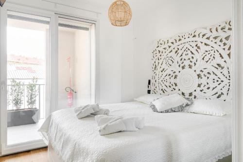 a white bedroom with a large bed and a window at Certosa District - Modern Flat & Free Box Parking in Milan