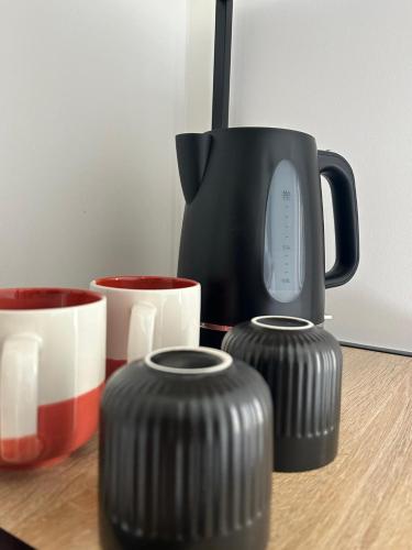 une cafetière noire et deux tasses sur une table dans l'établissement Love room les étoiles du désir, à Périgueux