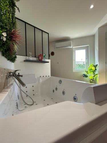 une salle de bain blanche avec une baignoire et un lavabo dans l'établissement Love room les étoiles du désir, à Périgueux