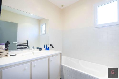 un bagno bianco con lavandino e specchio di Maison de vacance avec jardin 8 personnes Biscarrosse a Biscarrosse