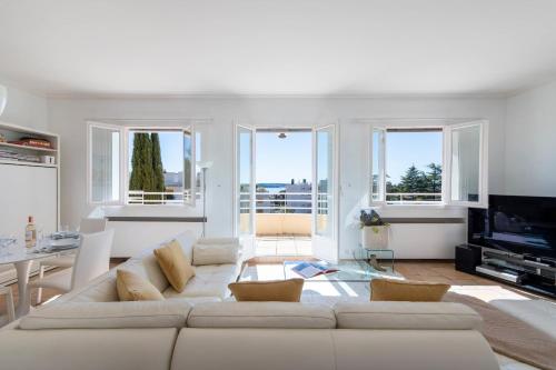 - un salon avec un canapé blanc et des fenêtres dans l'établissement UNIQUE! 2-Br Apartment with Pool & Rooftop, à Cannes