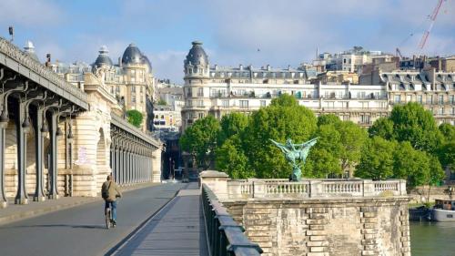 une personne faisant du vélo sur un pont avec des bâtiments dans l'établissement Studio de charme quartier tour eiffel - 2P, à Paris
