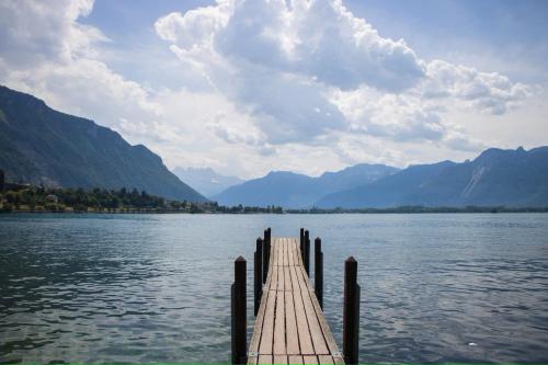 a dock on a lake with mountains in the background at Côté Lac Hostel Evian in Évian-les-Bains