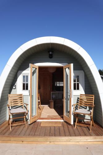 an arched patio with two chairs on a deck at Huisje Vigga - knus houten tiny house in Anloo