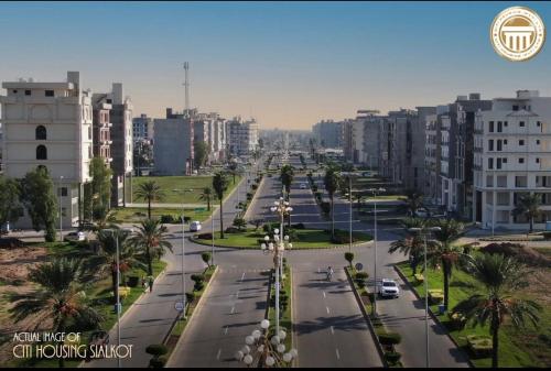 an empty city street with palm trees and buildings at Urban Apartments in Sialkot