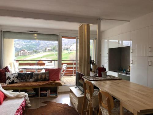 une cuisine et un salon avec une table et un canapé dans l'établissement Les alpages - lit queen size - centre station, à Enchastrayes