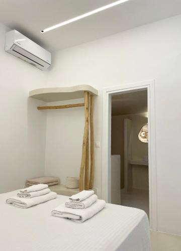 a room with a bed with white sheets and towels at Faros Residences in Faros
