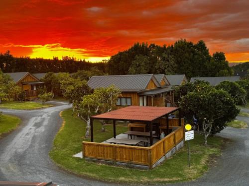 a house with a gazebo in front of a sunset at Kerigold Secluded Chalets Motel in Kerikeri