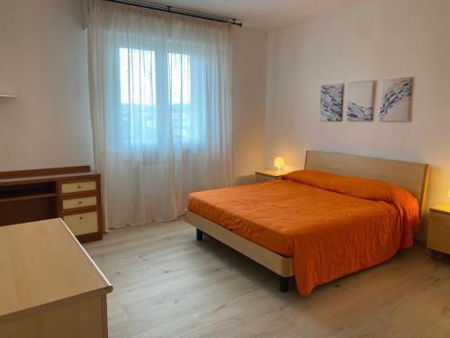 a bedroom with a bed with an orange blanket and a window at Casa Eva in Bibione