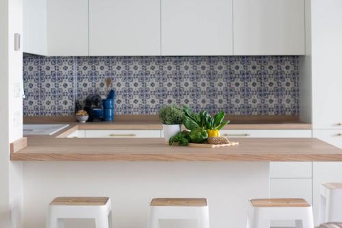 a kitchen with white cabinets and a counter with two stools at Casa Alyx by PortofinoHomes in Santa Margherita Ligure