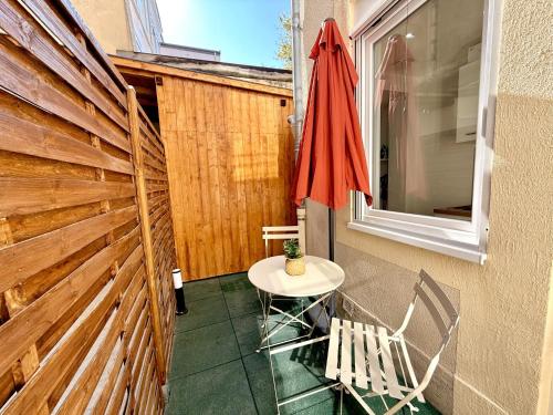 un patio avec une table, des chaises et un parasol dans l'établissement Oasis Marocaine avec Terrasse Privée, à Reims