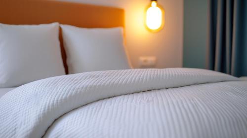 a close up of a bed with white sheets and pillows at Best Western Plus Neepawa Hotel in Neepawa