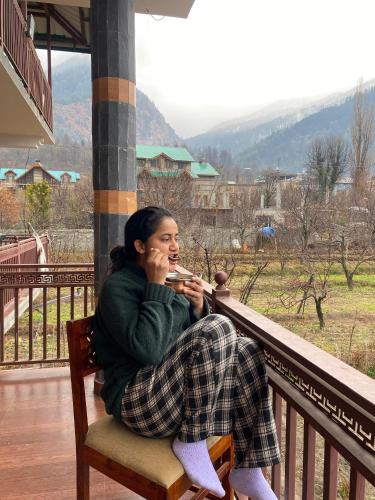 a woman sitting on a balcony talking on a cell phone at North Katmor homestay in Haripūr