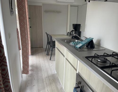 une cuisine avec un évier et une cuisinière four supérieur dans l'établissement MOBIL HOME l'ARLEQUIN, à Valras-Plage
