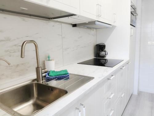una cucina con lavello in acciaio inossidabile e mobili bianchi di Cristimar Roja Beach a Los Cristianos